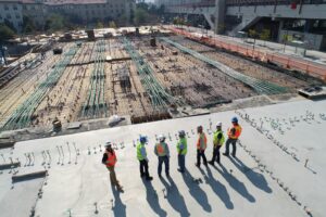 A group of individuals wearing hard hats overlook a construction site.